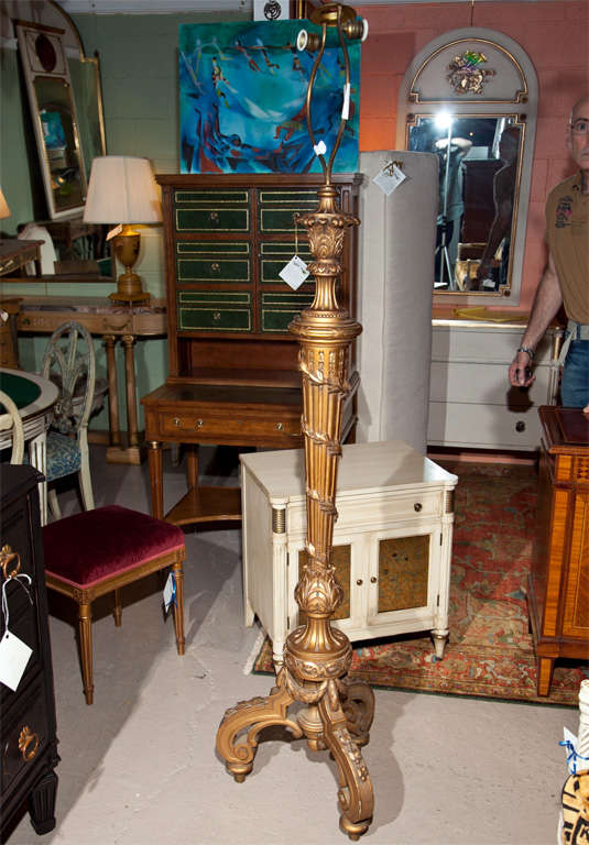 French giltwood floor lamp, elegantly carved candelabra style floor lamp, overall gilded, single pedestal on a triangular base.
