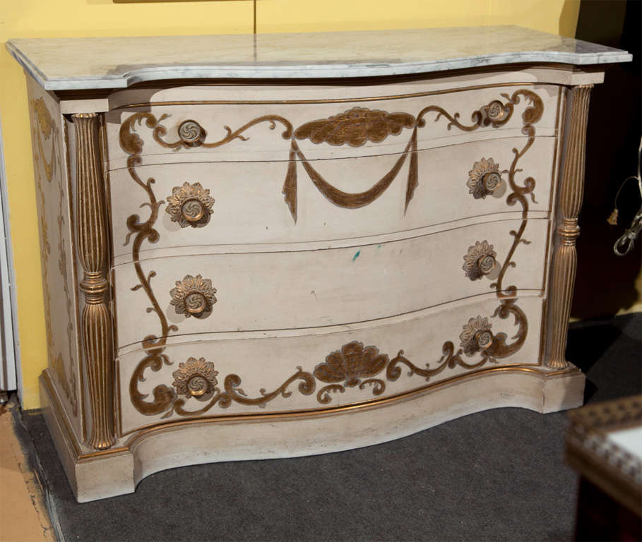 Pair of attractive French commodes, circa 1950s, the white serpentine marble atop a white distress-painted and parcel-gilt conforming case, fitted with four graduating drawers decorated with painted scrolls, flanked by fluted balusters, raised on