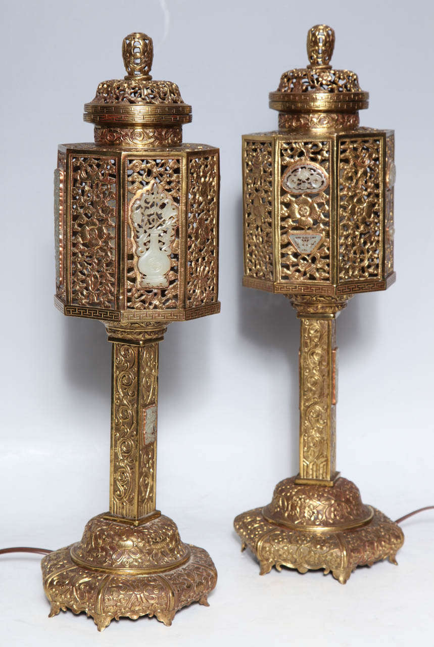 A pair of gilded bronze Chinese lanterns in traditional style with inlaid Jade Plaques. The design of the fret work includes floral motifs as well as meandering Prunis Blossoms. The jade plaques fit nicely with the overall themes of finely crafted