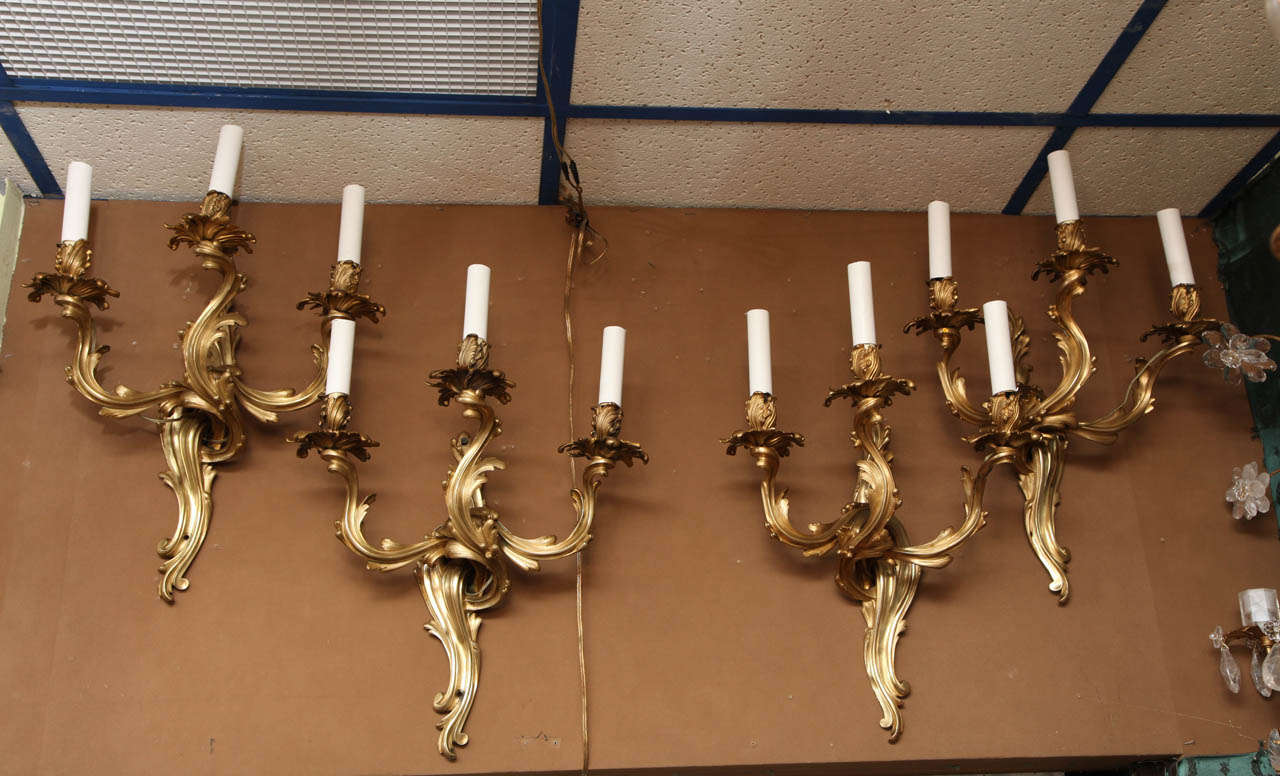 A very fine quality set of four French Louis XV style bronze three light wall sconces.
