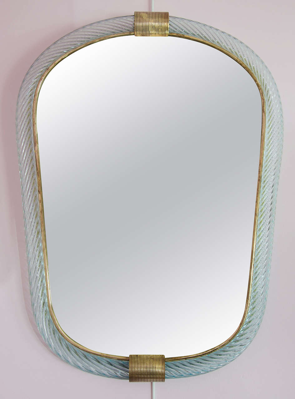 Elegantly shaped soft blue wall mirror with handcrafted twisted glass with brass surround and ribbed brass detailing.

A pale green matching piece is also listed.

Barovier and Toso was formed in 1936 with the merge of two glasshouses, Vetreria