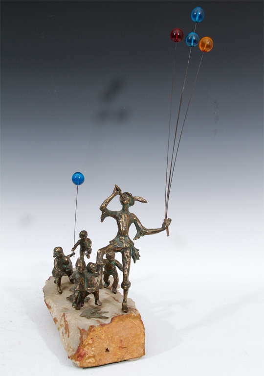 A lively Curtis Jere interpretation of the Pied Piper carrying balloons with village children in pursuit. The burnished bronze figures are mounted in a slab of white and orange agate. The brightly colored lucite balloons swing gaily on thin metal