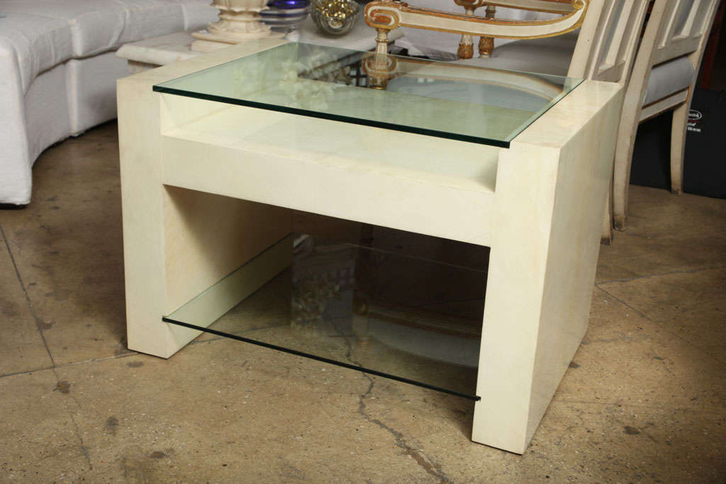 A large lacquered parchment-covered table with a glass top and a low glass shelf. Use as a side or end table. Only one still available.
