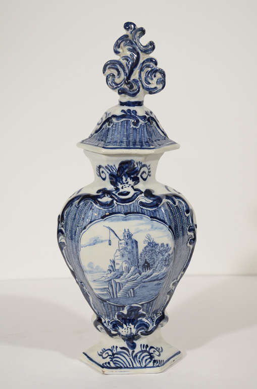 An elegant pair of late 18th century Dutch Delft Blue and White garniture vases tall and thin with broad shoulders and a flaring foot. They show a castle at the water's edge. The shoulders and cover of each vase are decorated with blue and white