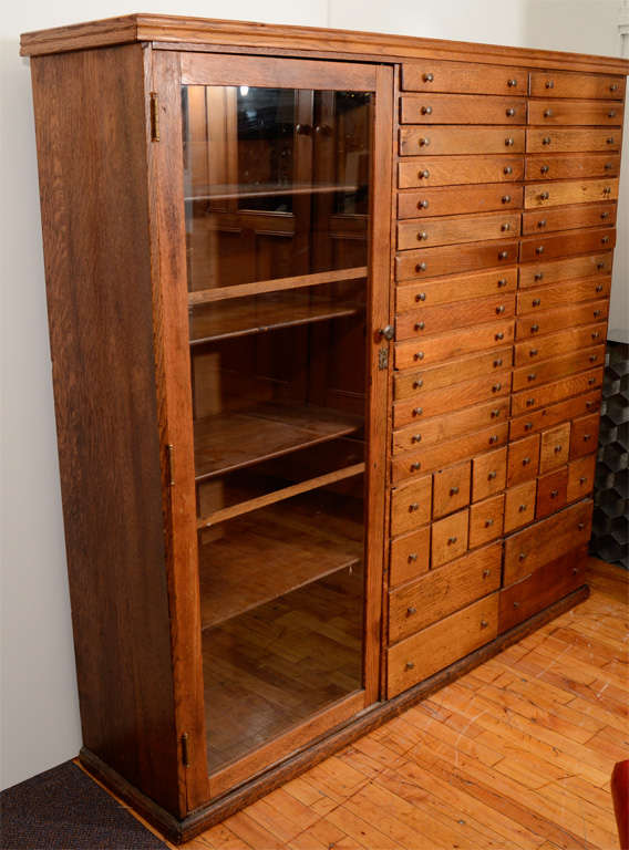 An elaborate Mission apothecary cabinet with 44 drawers of varying shape and size a glass door side cabinet with shelves. The drawers have a locking mechanism accessed in the glass front cabinet which can be key locked. T

The piece is in vintage