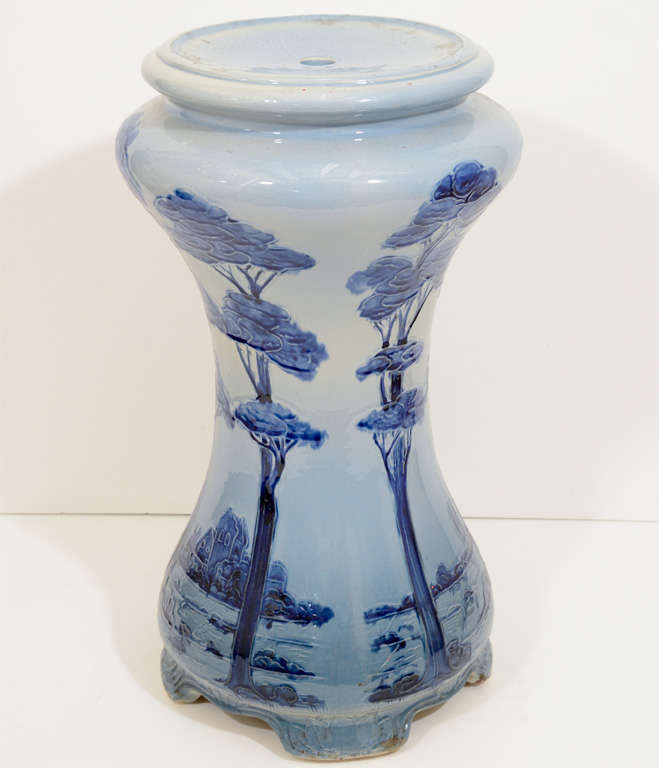 A vintage baluster form table base in blue and white ceramic, depicting tall trees against a landscape, detailed with artful incising. Good condition, with age appropriate wear.