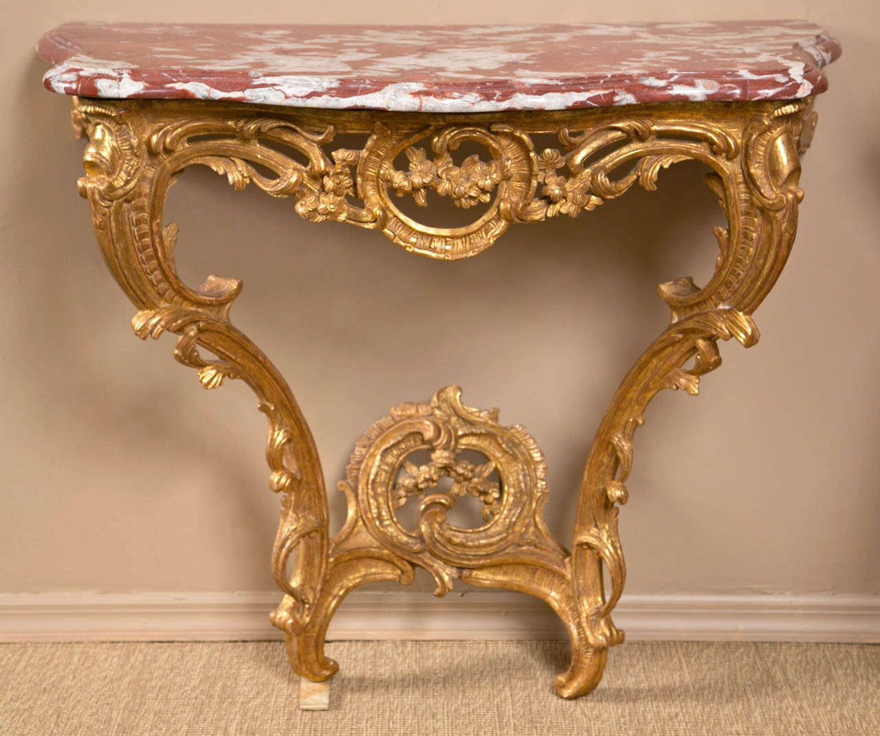 A French, Louis XV carved giltwood console table with a rouge marble top.