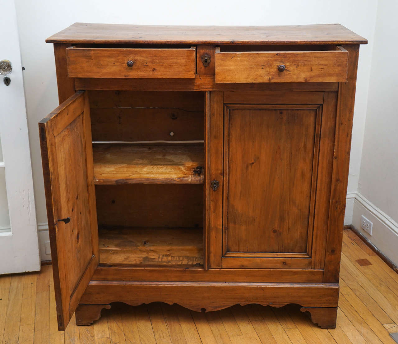 The French reddish cast pine is an eye stopper. Different than the mustard color English pine, this piece has an original key and lock and one original shelf inside. There is a nice sweet scallop on the bottom and bracket feet.