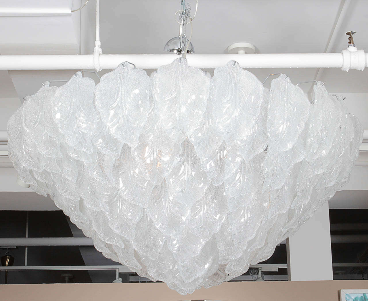 An Italian Murano glass chandelier comprised of a seven tier chrome frame of descending circumference from which approximately one hundred 10-inch white textured semi-opaque hand blown leaves are suspended, seven sockets and newly wired for the