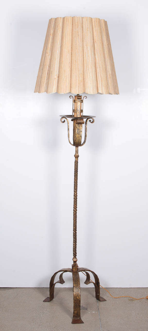 A gilt wrought iron torchiere converted and electrified into a floor lamp.  French, 19th Century.  Includes vintage raffia shade, circa 1940.  Wired for U.S.; takes one standard base bulb, 100 watts max.

Dimensions:
74 inch height
Shade: 18