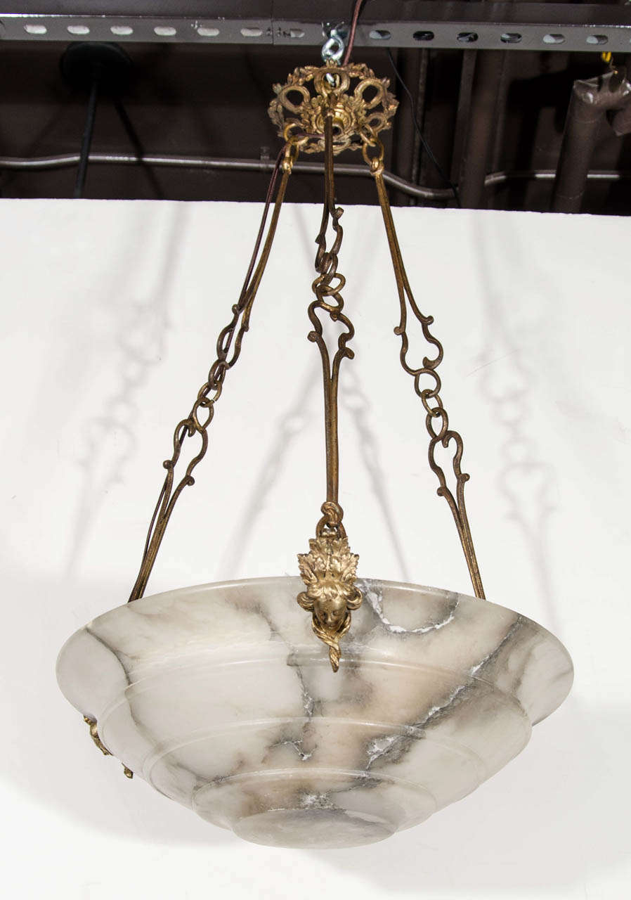 Beautiful Art Deco light fixture with stepped dome design in alabaster in hues of white marble with grey and sand colored veining. The chandelier features three-sided chain links with elegant incised hand-forged designs over gilded bronze metal. The