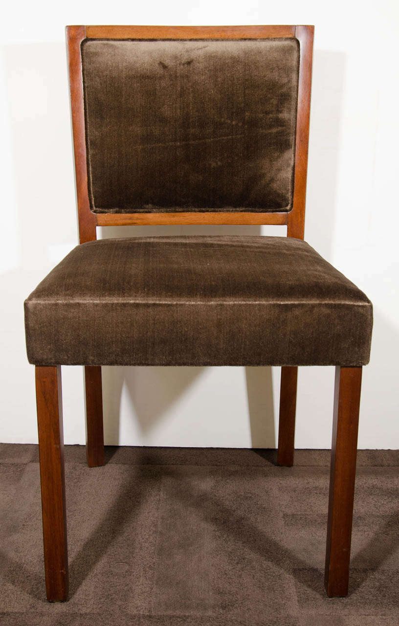 Set of eight modernist dining chairs with low square back design. The chairs have a beautiful streamline design with clean lines and comfortable seating and backs.  The chairs have walnut wood frames in a medium brown finish and have been newly
