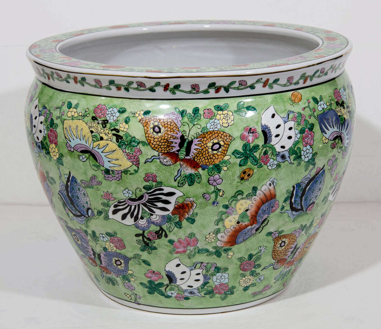 Exceptional large 19th Century Chinese fish bowl or jardiniere in underglaze porcelain.  The bowl has famille verte exterior with rich decorative details throughout, depicting a multitude of butterflies and floral forms in an exquisite array of