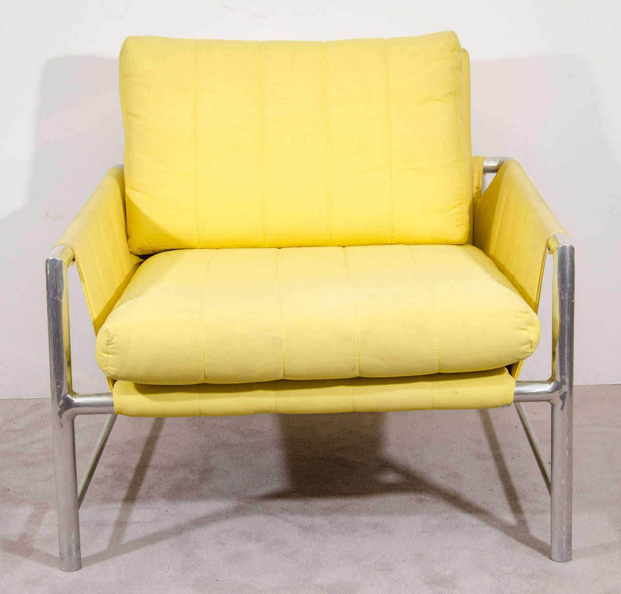 A vintage metal armchair in the style of Milo Baughman upholstered in lemon yellow fabric.  Good vintage condition with some scratches to the fame and some spotting to the upholstery.
