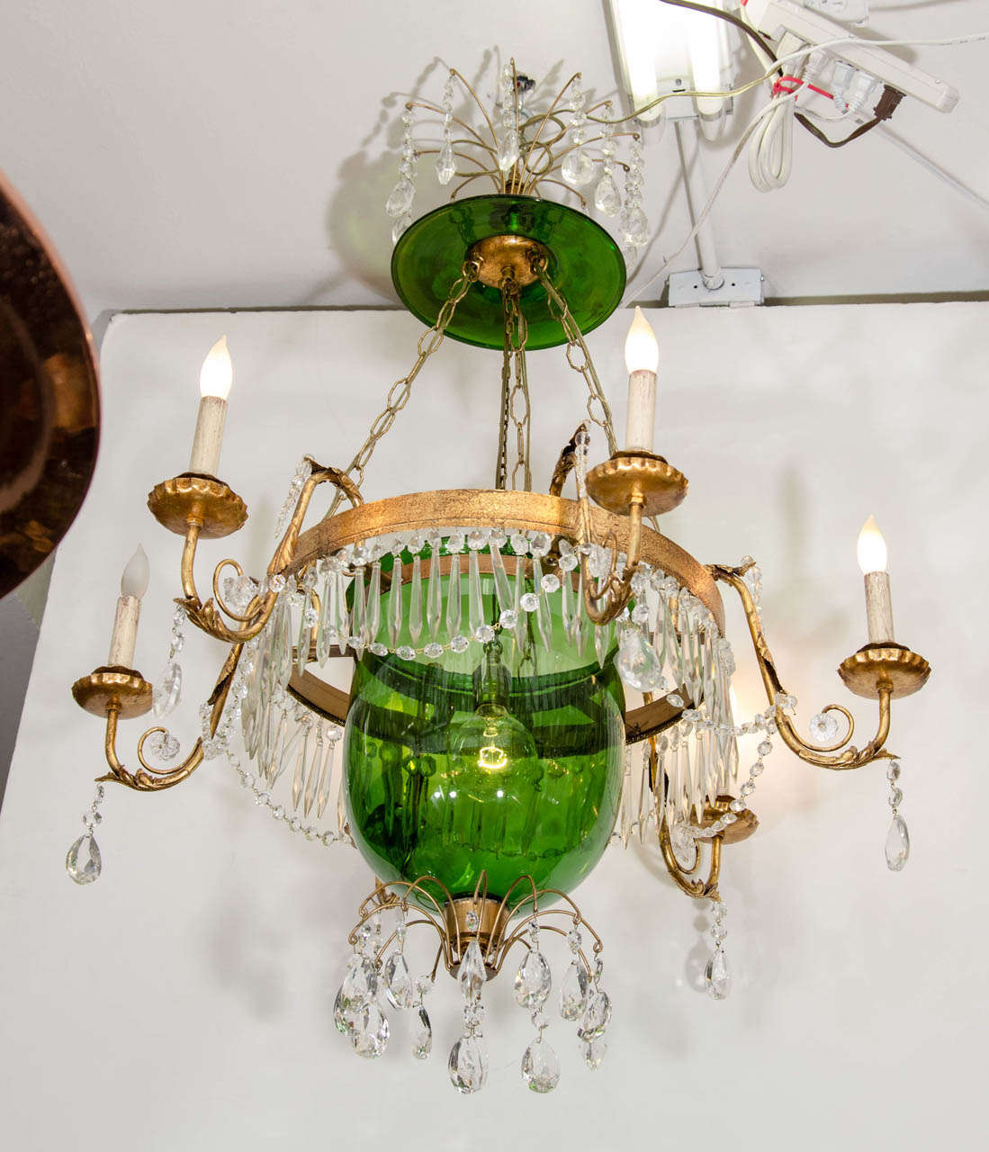 A vintage four-light green glass bell jar chandelier with crystals suspended from an ornate gilded metal frame.