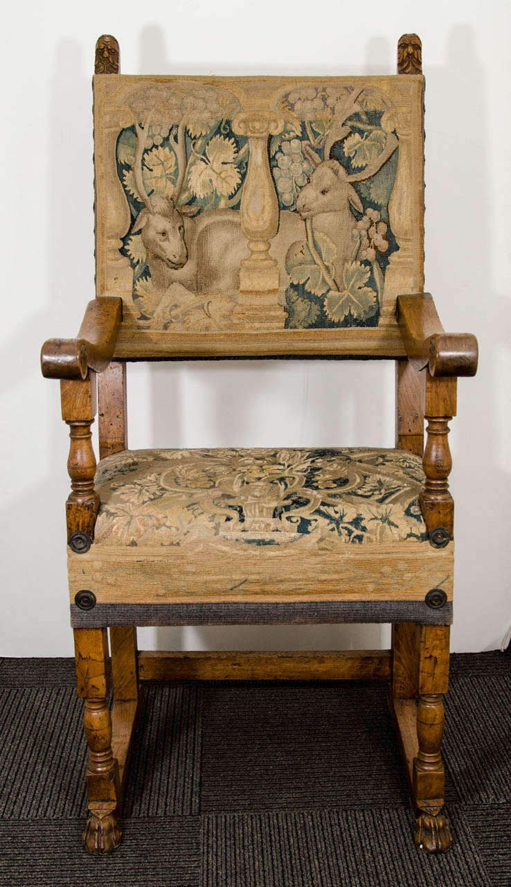 A 19th century Jacobean style wooden armchair with carved hoof feet and male faces.  Original tapestry upholstery depicts two seated deer among leaves and berries.

Good condition with age appropriate wear.  There are some nicks and scratches to