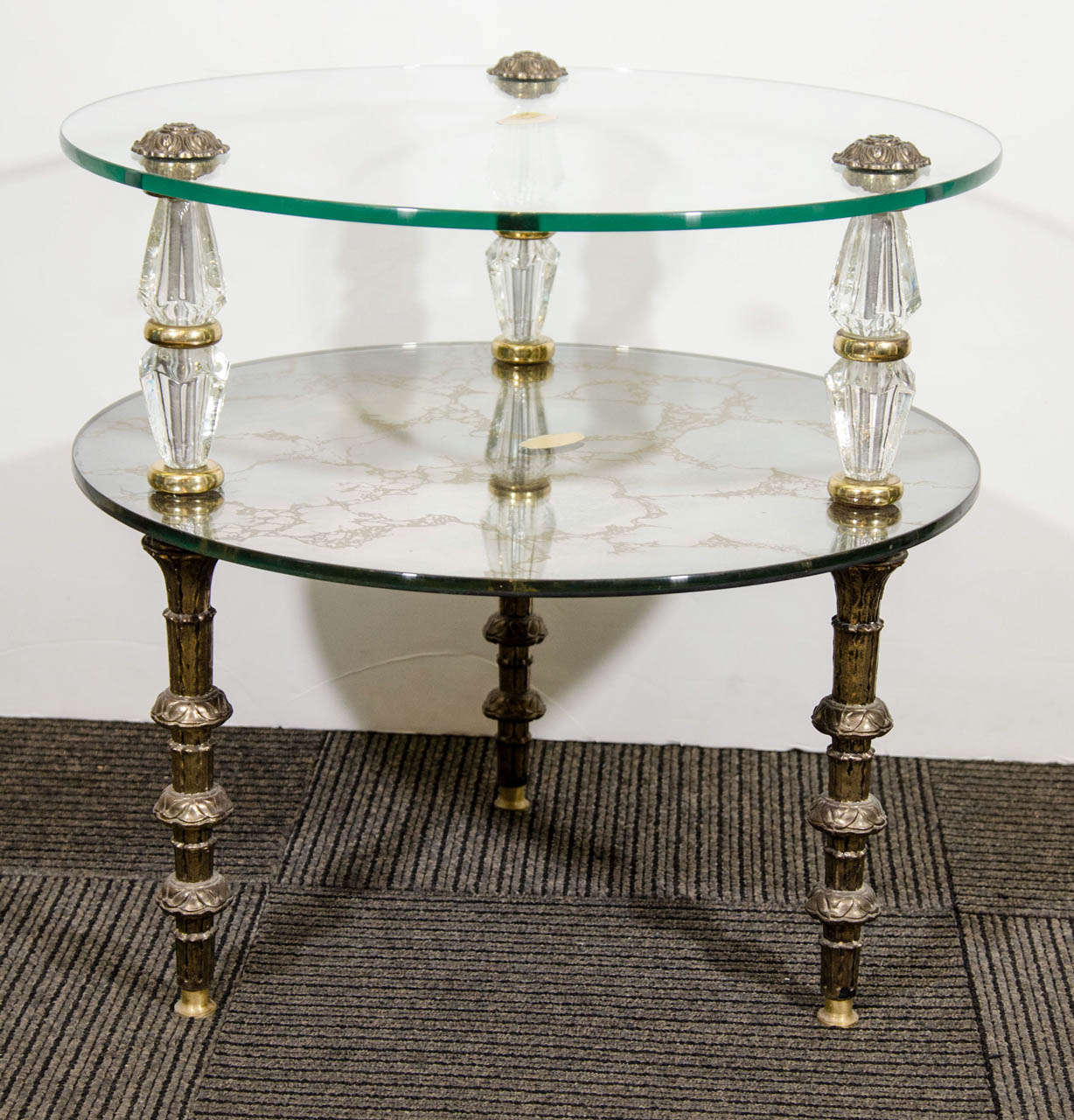 A vintage pair of two-tier side and end tables, produced in Belgium by Goran Manufacturing Co. Inc, circa 1950's, with two glass and églomisé round tops, supported by beautiful, classically formed legs in brass and faceted glass. Good vintage