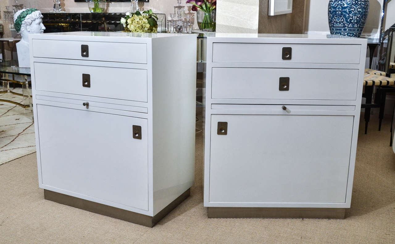 Interesting pair of Mid-Century white lacquer nightstands with two drawers, cabinet and pull-out shelf.