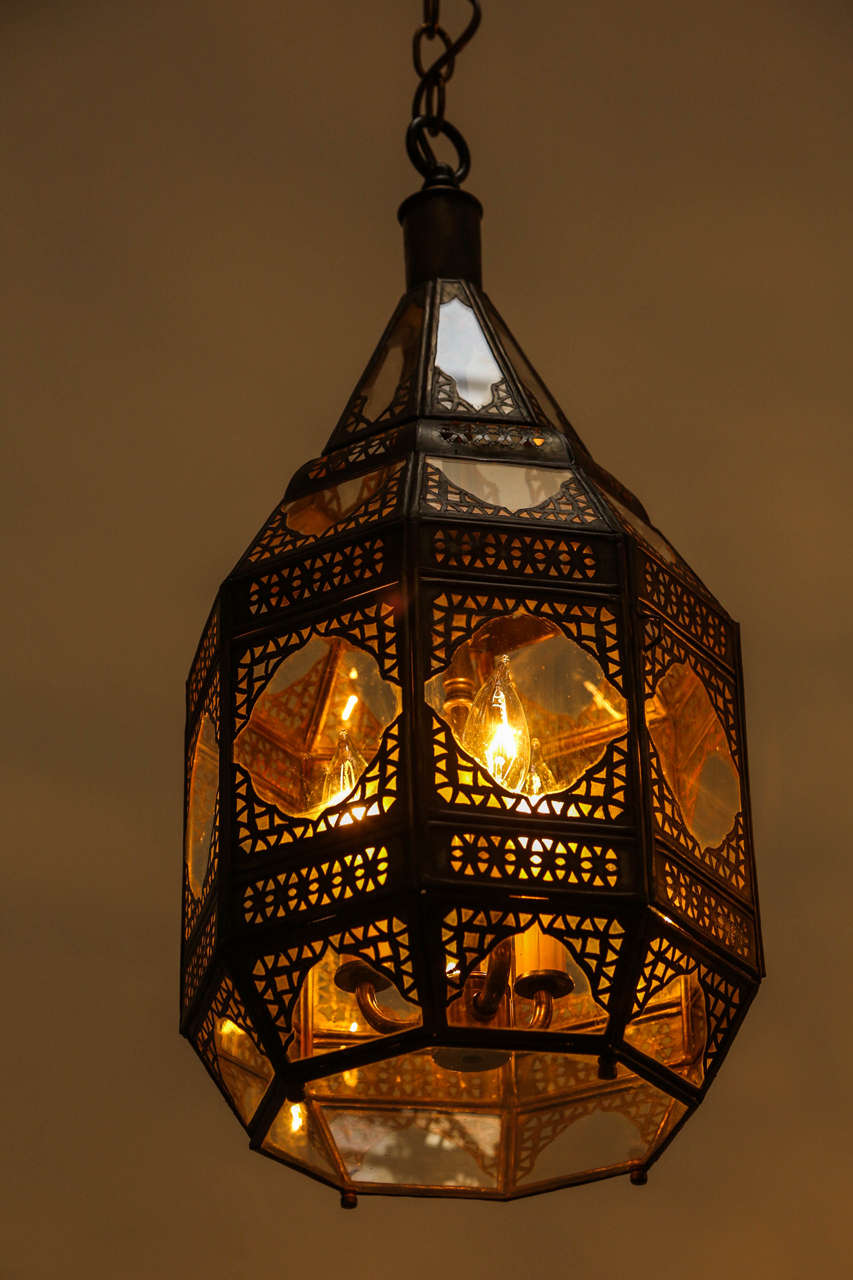 This is a smaller version of our Moroccan Moorish clear glass lantern with intricate metal filigree.
Octagonal shape, delicately handcrafted by artisans in Morocco. Bronze metal color finish. Could be used hanging from the ceiling or seating on a