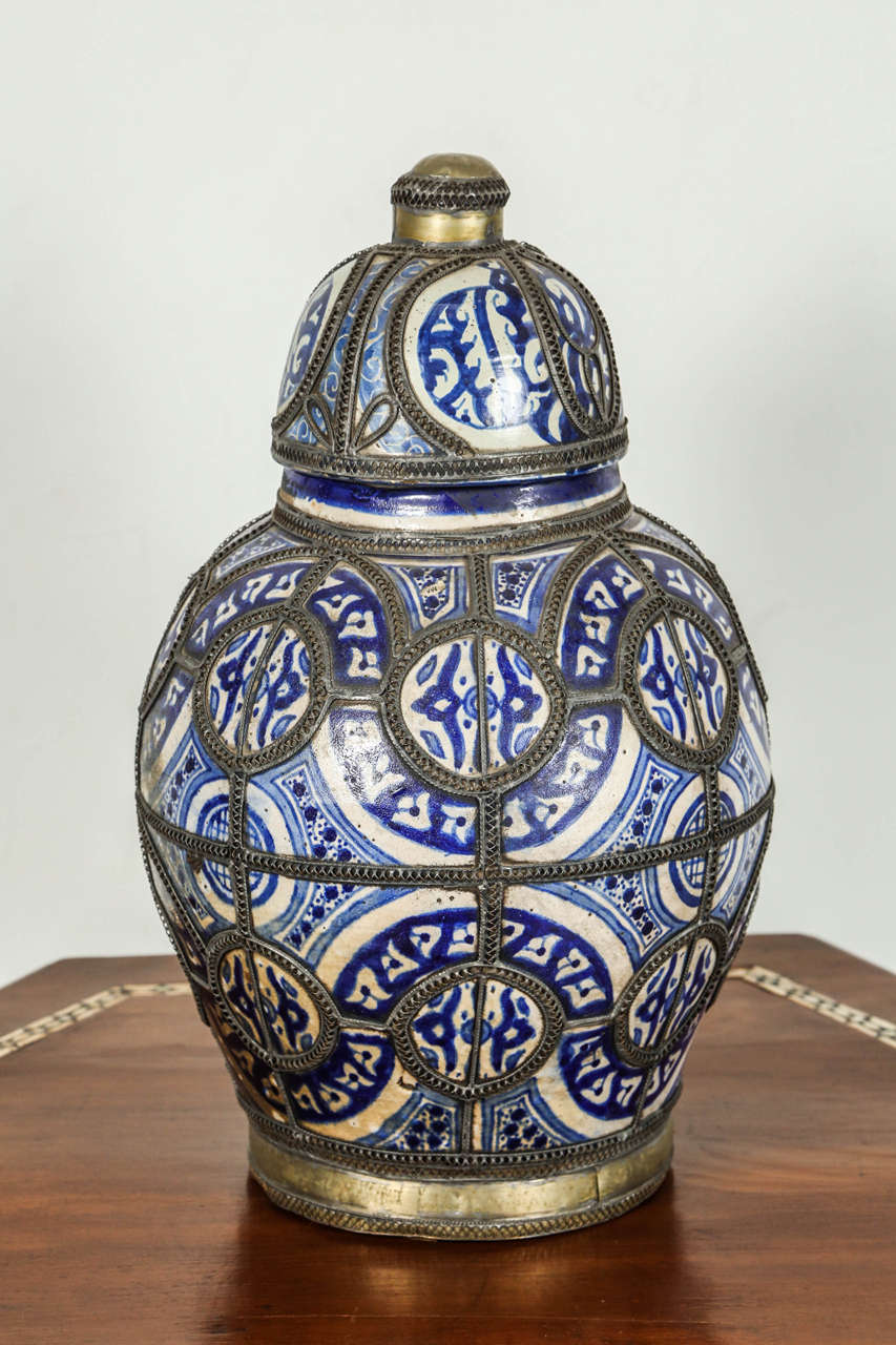 Antique Moroccan  blue and white ceramic urn with lid from Fez.
Moorish style handcrafted lidded jar adorned with fine filigree silver nickel work
Antique Hispano Moresque design ceramic jabana on ceramic bleu de Fez urn.
Museum quality.
Handcrafted