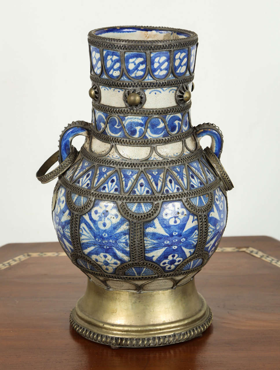 Antique Moroccan ceramic vase from Fez.
Moorish style handcrafted vase adorned with fine filigree silver nickel work, with two handles.
Antique Hispano Moresque design on ceramic bleu de Fez urn.
Museum quality.
Handcrafted in Fez, Morocco circa