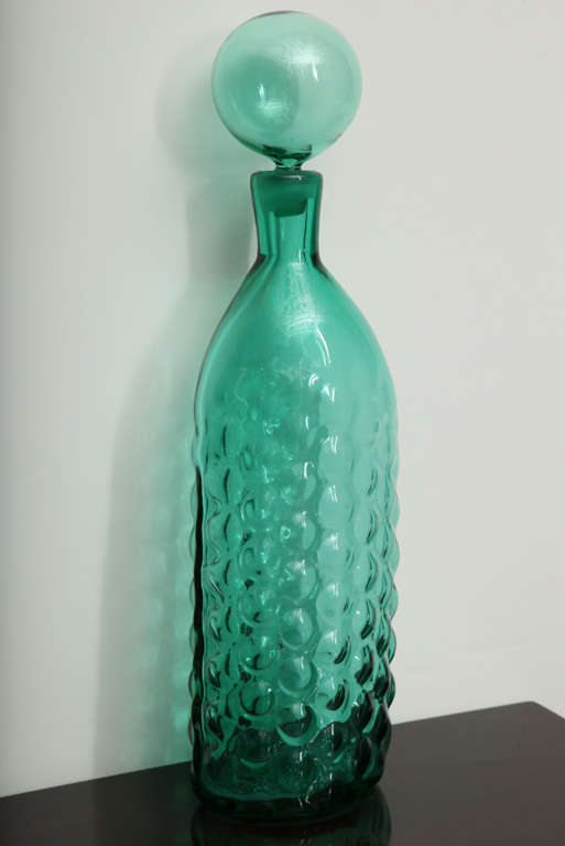 Gorgeous, hand blown bottle with relief bubbles to exterior sides and beautiful, large bubble stopper top.  Emerald color, and only in production for a few years in the 1960's.  A great graphic piece for any table scape.  Signature on underside