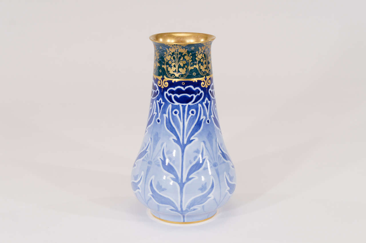 This striking Doulton Burslem porcelain vase is a wonderful example of Art Nouveau/Arts and Crafts decoration. The blue and white transfer body with a teal blue contrasting band is highlighted with raised paste gold with additional gold at the rim