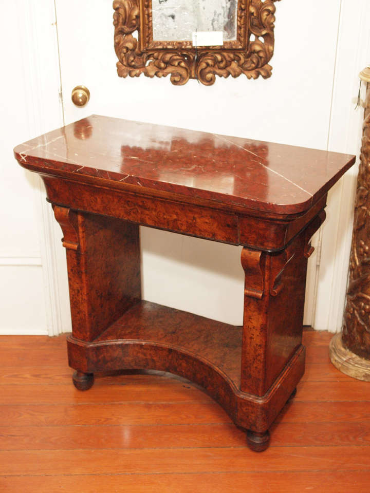 French Charles X burl walnut petite console table with rouge marble top. The top frieze having an ogee shape and one drawer bracketed on two plinths with a concave base on bun feet.