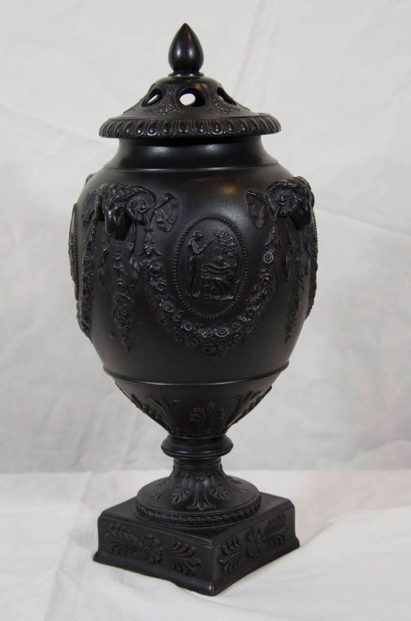 Made for potpourri with piercing in the cover each vase has molded neoclassical designs featuring ram's head terminals on the shoulders and a variety of classical figures in oval cartouches.
Black Basalt was created by Josiah Wedgwood in the 18th