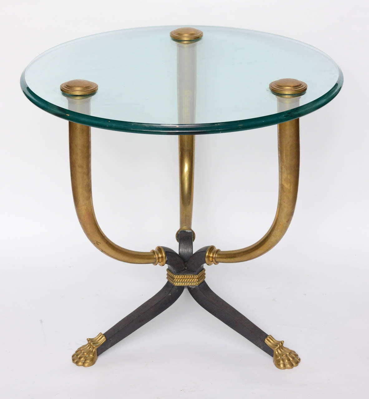 The glass top with brass caps over three curved supports joined by a patinated bronze stretcher wrapped in gilt bronze rope end in gilt bronze lion paw feet.