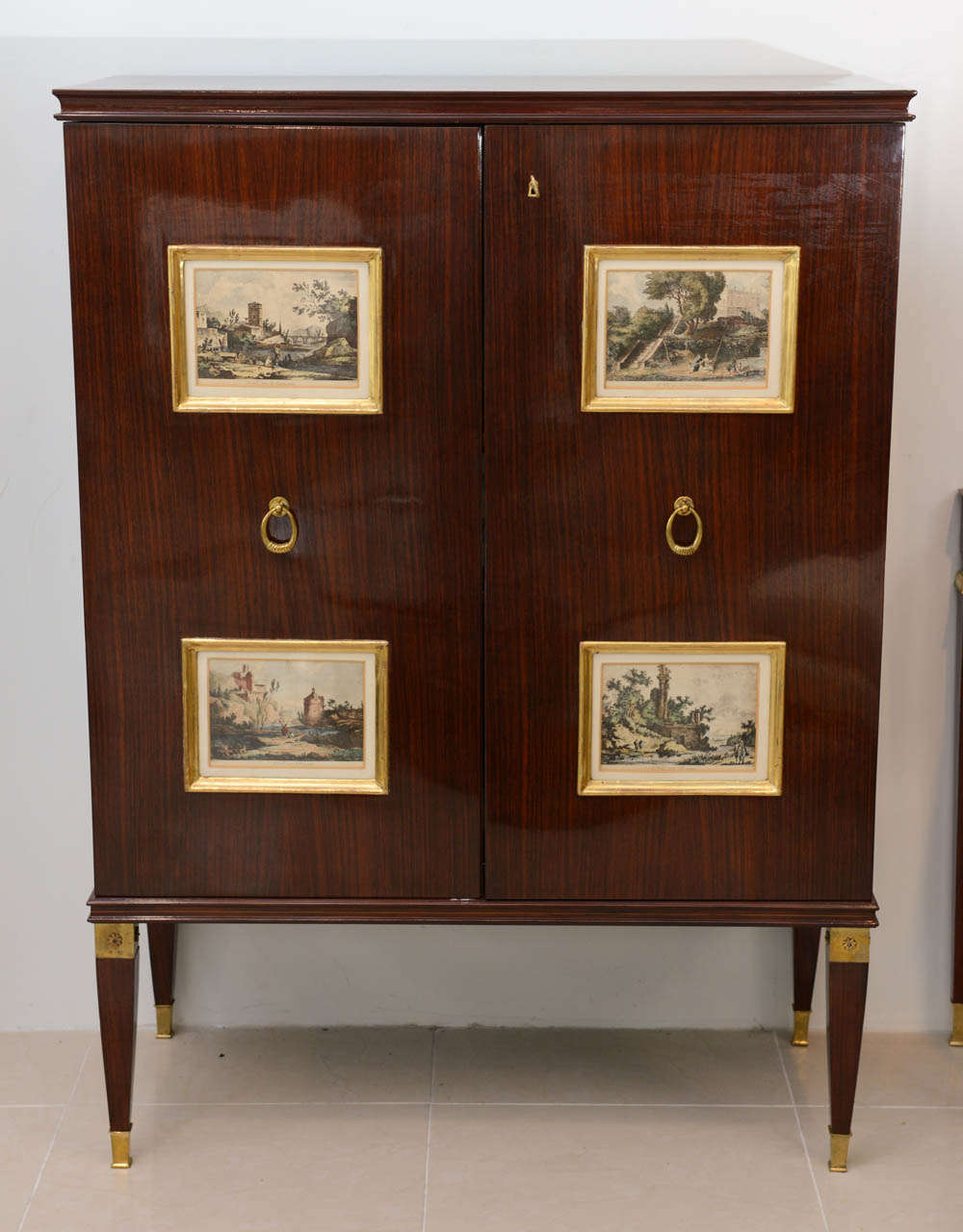 The rectangular top over two doors with giltwood panels inset with 18th century engravings of classical scenes, on square tapering legs headed with gilt bronze mounts with star motif, terminating in sabots, the interior finely fitted with drawers