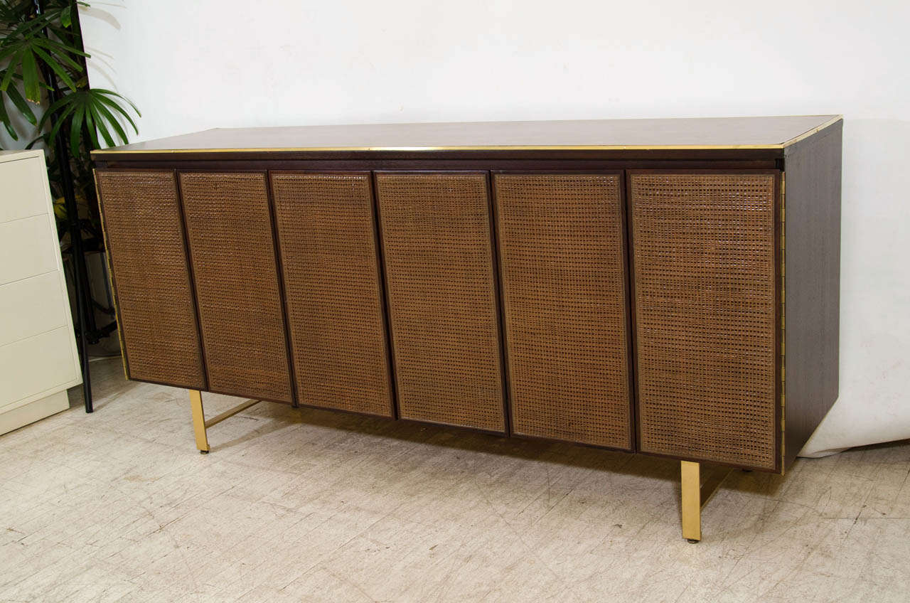 Very handsome, nicely styled credenza by Paul McCobb for the Calvin Group. Refinished in a dark espresso stain and beautifully accented by brass trim and uncommon brass legs. The trifold doors have caning. Remarkable! Please contact for location. 