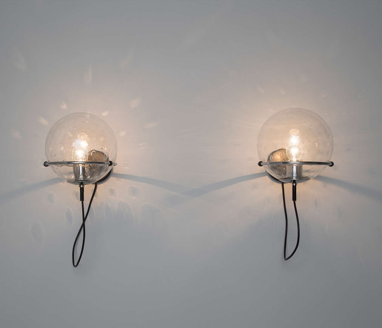 Six 'Globe' wall lights with a black coated metal wall-mounted system.

The transparent glass orbs are well made with a small 'bubble' pattern within the glass, which provide a very ambient light. This item is available in large quantities. Feel
