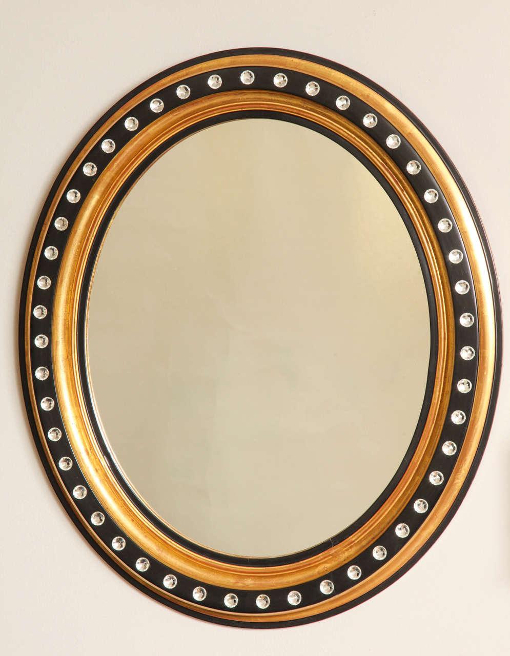 An oval Irish Georgian Style mirror with gilt frame, having black contrasting detail decorated with faceted crystal rosettes. The 1920s frame newly finished and decorated.