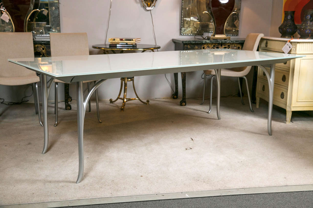 A very fine and sleek Roche Bobois dining table with extendable leaf. This custom quality table with a tempered-glass top and steel base finished in anthracite epoxy. One hidden retractable wooden leaf. The table  purchased from a Westport CT home