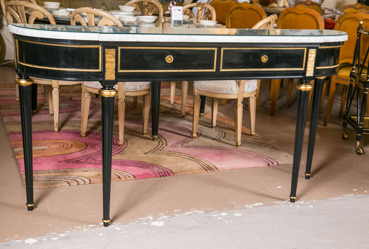 A fine ebonized marble-top Louis XVI style console by Maison Jansen. This piece reflects the beauty of a bygone era. The Louis XVI style legs having fluted tapering design terminating in a bronze cap. The apron having all around bronze framing with