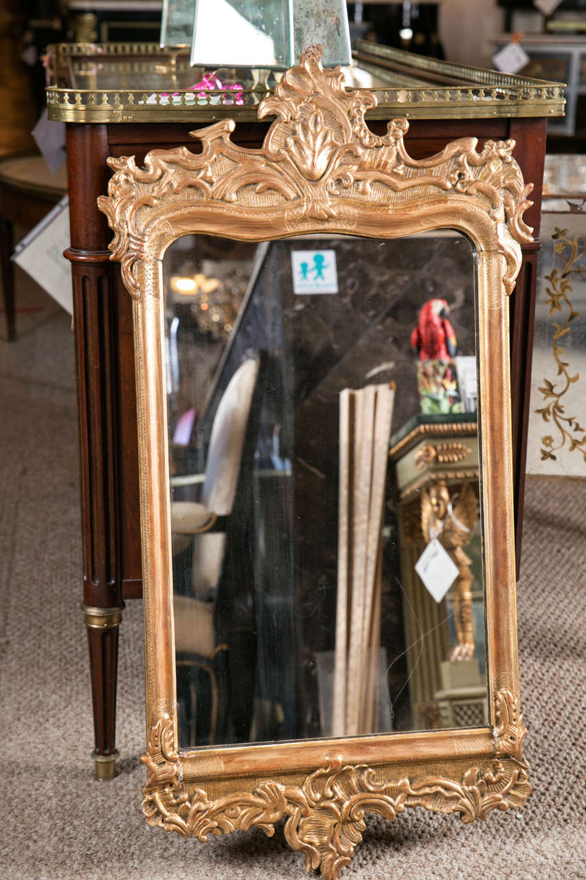 Pair of 19th century Rococo carved wall mirrors. Wonderfully sized wall mirrors with scrolled leaf cartouche crests. The central framed mirror panel in a fine solid wood carved frame. The upper and lower portion having heavily carved wood work. Each