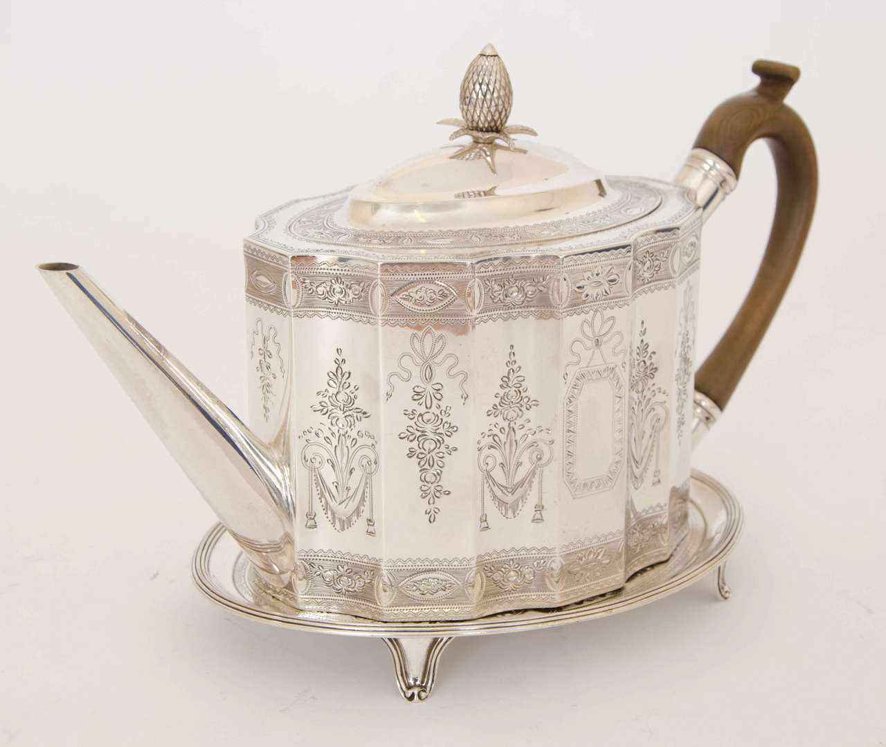 A George III shaped oval Tea Pot and oval Stand both bright-engraved to match. The pot is made by Cornelius Bland of London in 1788 , the stand is made by Thomas Hannam & John Crouch of London in 1788. The total Height of the pot and stand is 7