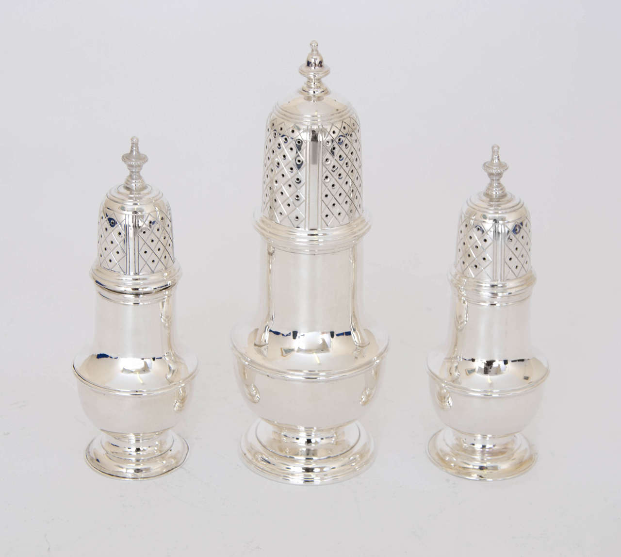 A suite of three George II Antique Silver Casters, I sugar and 2 peppers of circular bellied form, with pull-off covers and knop finials. Each one stands on a circular foot.  Height of Sugar Caster 6.50 inches 16.5 cm, Peppers 5 inches 12.5 cm