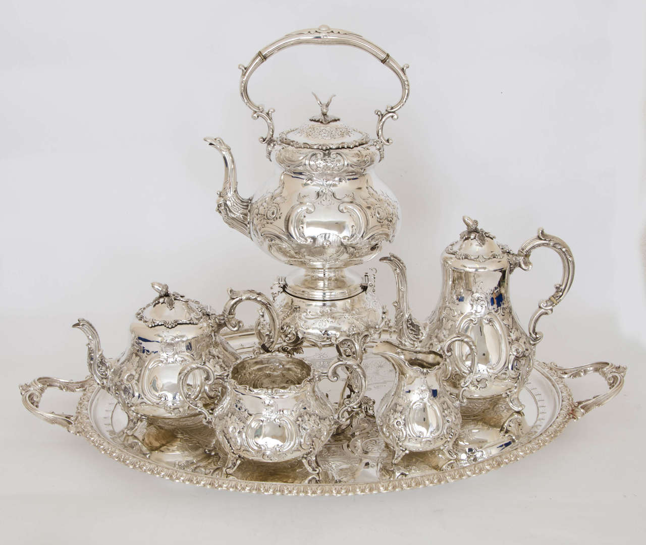 A Victorian Antique Silver four –piece tea and coffee service made by Thomas Smily of London in 1859; together with an Electroplated Kettle on stand and all placed on a silver plated tray.  The tea and coffee pots are of inverted baluster form with