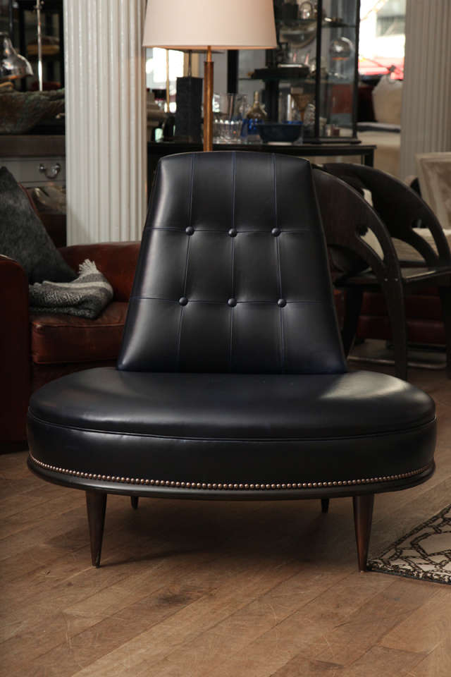 Tufted back oval lounge chair upholstered in black and blue leather with a sable finished base and nailhead trim circa 1960
