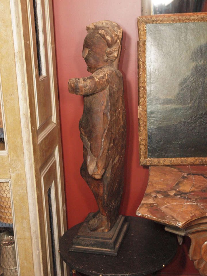 A 17th century Italian carved wood Putti carved from a single piece of wood.  A hole for the mouth suggests it may have been used as a fountain.  The statue sits on a metal base. Excellent patina.