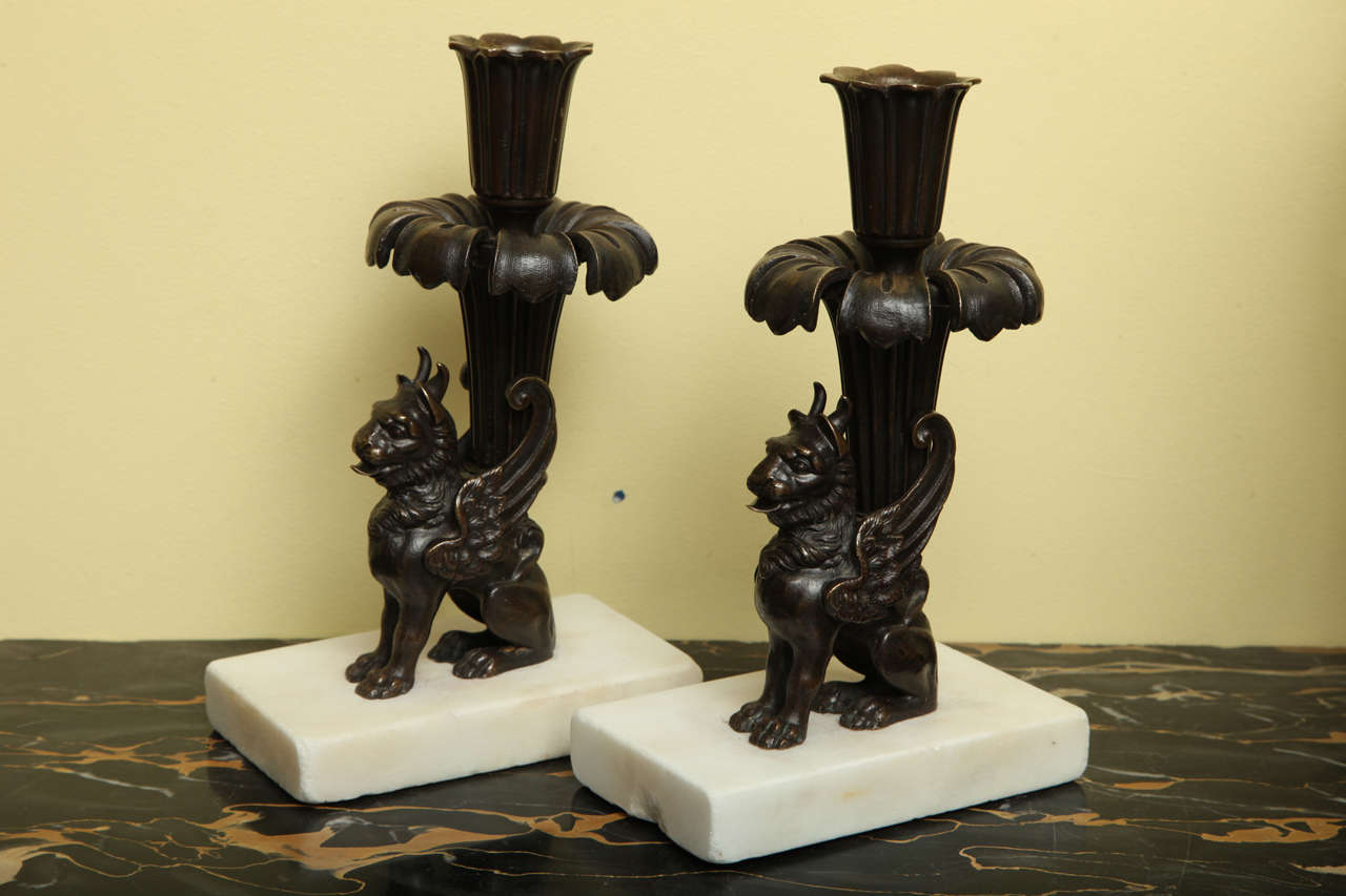 Very fine pair of Regency cast bronze seated griffin form candlesticks on rectangular white marble bases, beautifully cast and stipple chased on the original white marble bases, circa 1815.