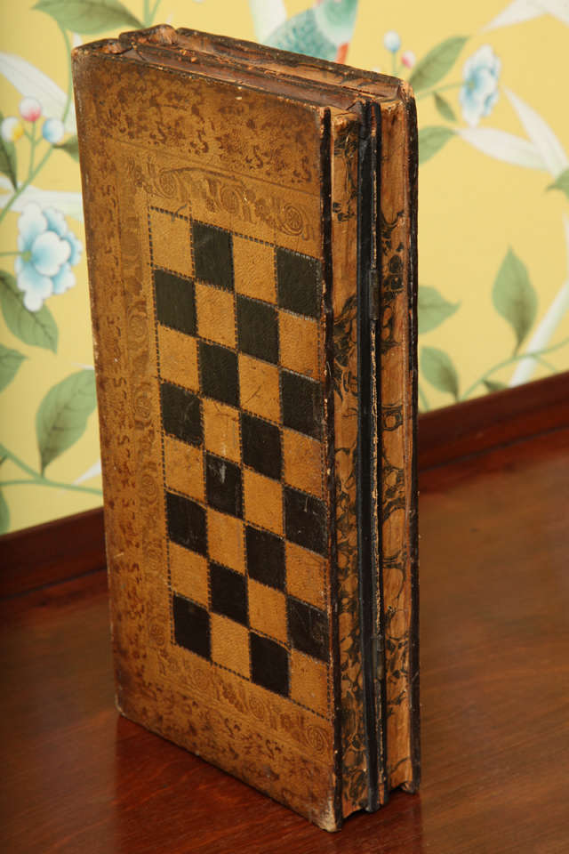 Victorian folding chess board in the form of a pair of books with gilt-tooled leather bindings and marbelized edges, opening to reveal a backgammon board with original dice shakers. Gaming pieces later replacements.  English c.1890
Height 12
