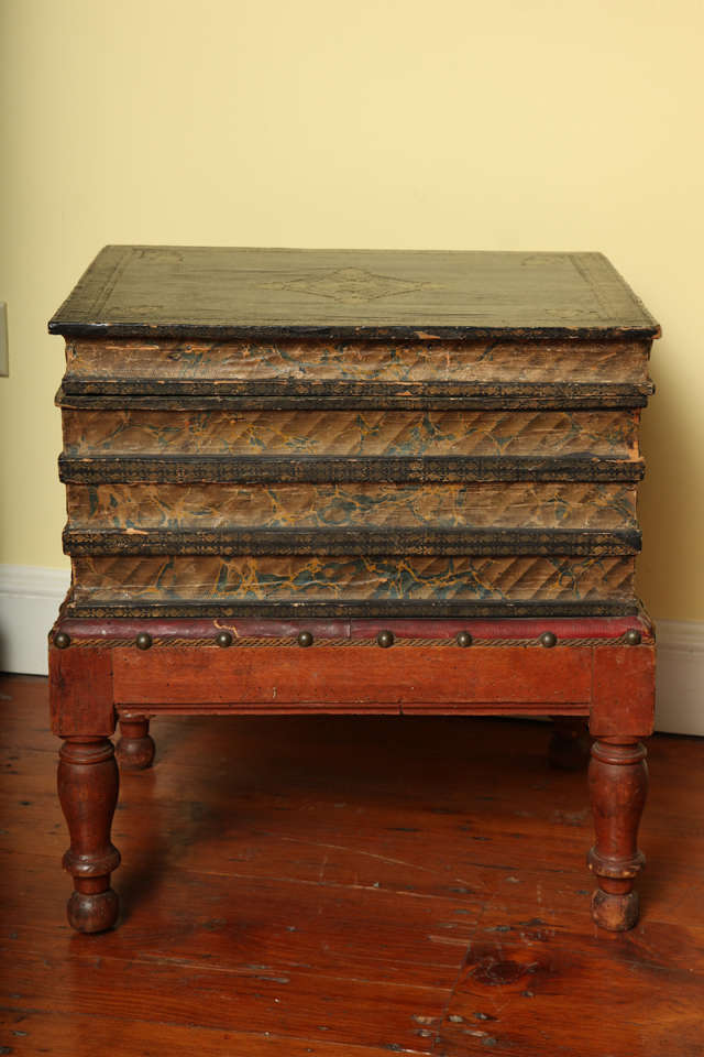 Victorian gilt tooled blue faux leather side table in the form of a stack of four books raised on a red leather cushion with applied trim and brass nailheads, on four turned red stained legs. The hinged 