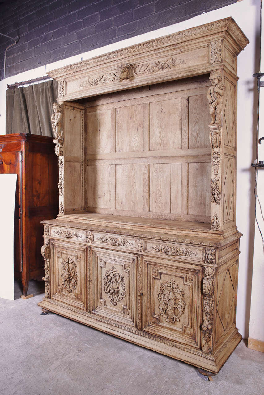 This stunning antique French stripped oak hunting deux corps has an upper portion with an open front *and a classical larger lower portion having three drawers and doors.  It is in the style of Louis XIII and features motifs of the hunt and putti