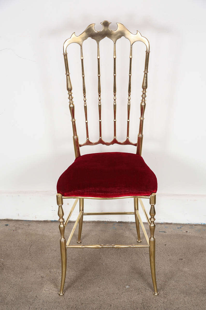 Pair of polished brass high back side chairs by Chiavari.
A wonderful handcrafted pair of polished brass side chairs with shapely crest rails and spindled backs and with red original velvet upholstery.
Designed by Giuseppe Gaetano Descalzi and