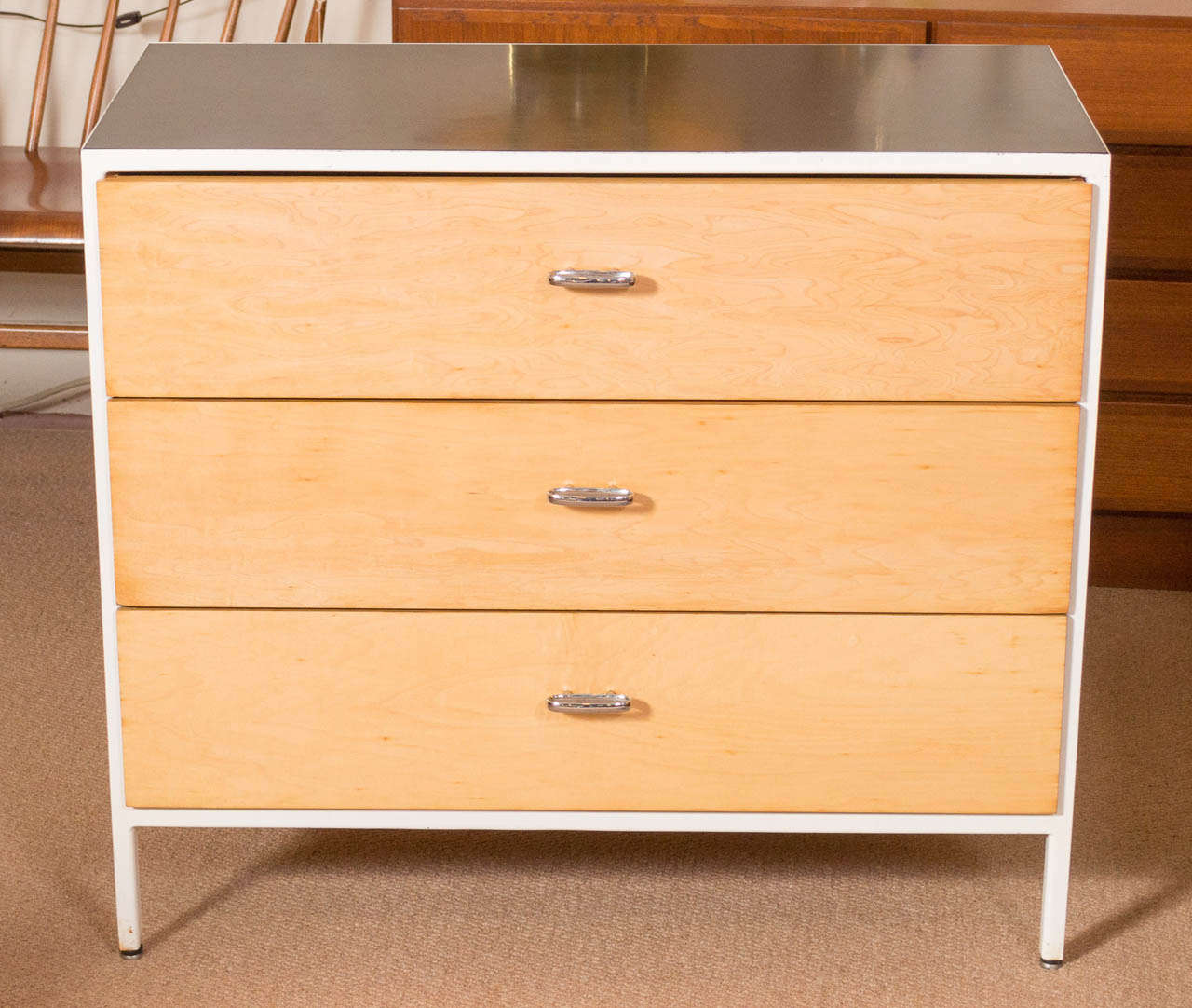 An iconic 1950's design by George Nelson, from the Steelframe line for Herman Miller. Dresser has three drawers,  white frame with a black formica top, the drawers have been refinished to it's natural wood. Does have a Herman Miller label on the