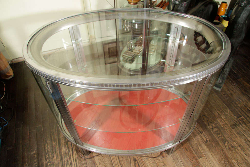 Nickeled bronze display cabinet with two glass shelves and red morocco leather on the bottom, French, late 1920s. There is a light that illuminates the interior.<br />
32