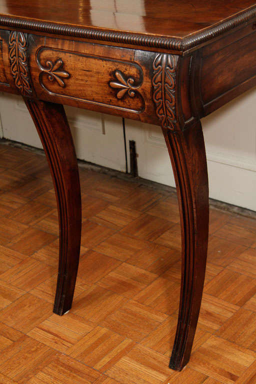 Irish mahogany server with six saber legs topped by single frieze drawer in front and two storage spaces on sides.  the frieze is decorated by foliate carving.